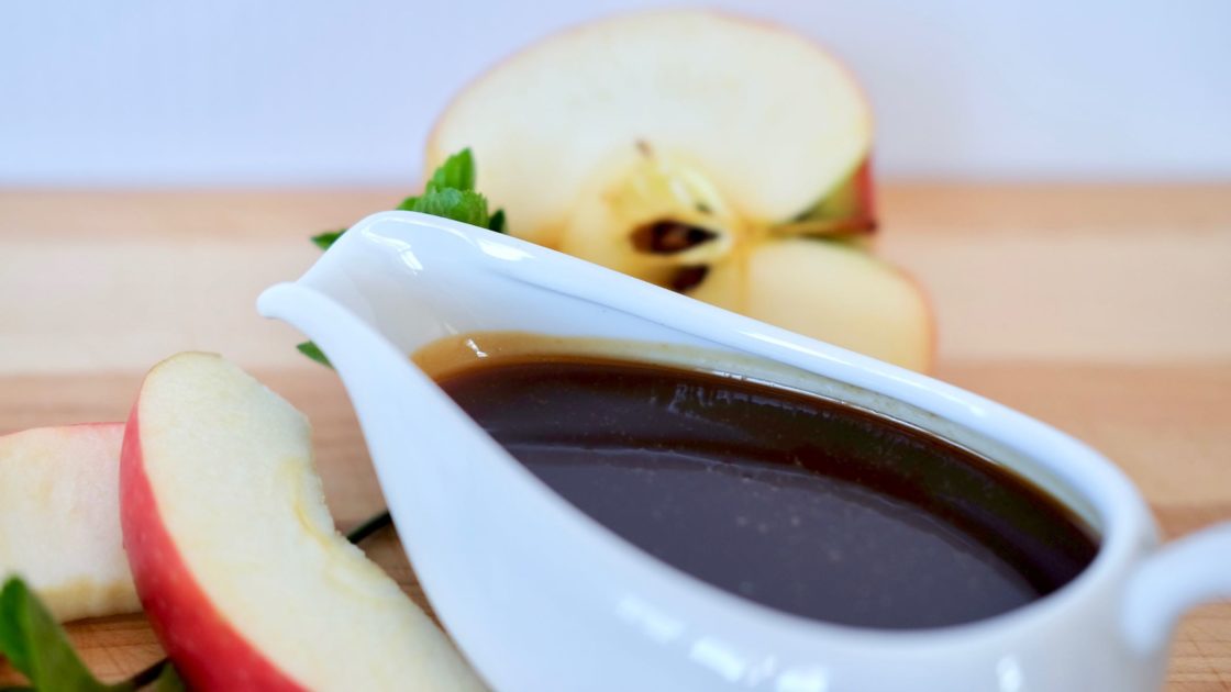 Apple Cider Caramel Sauce in gravy boat with Apple in background