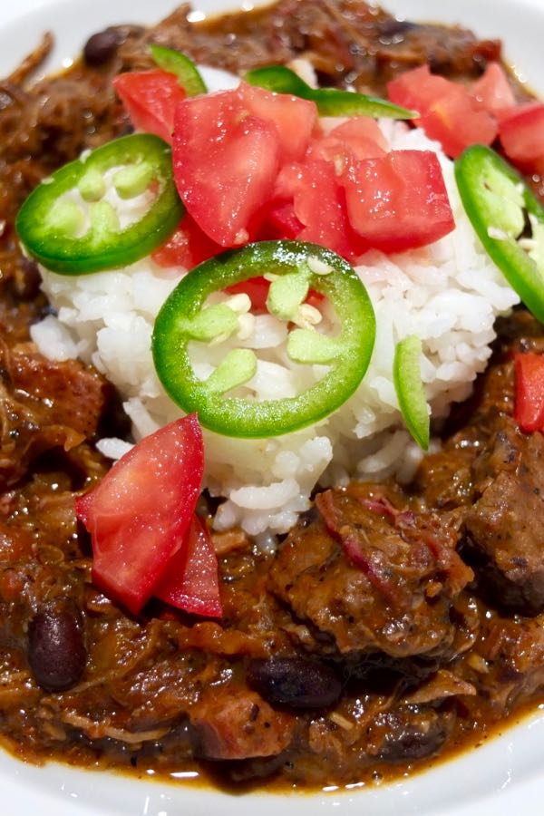  Feijoada with white rice garnished with chopped tomato and jalapeno slices.  
