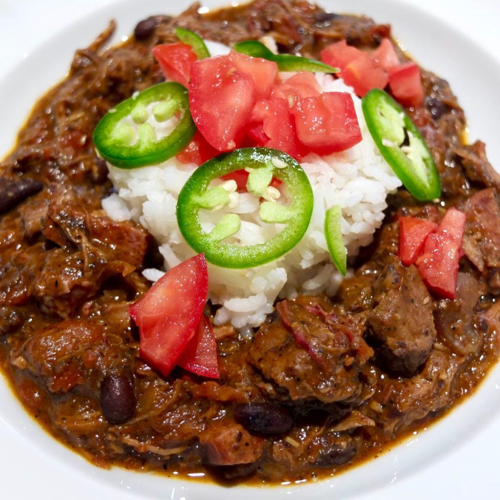 Feijoada served with white rice and garnishes with chopped tomato and jalapeno in White Bowl