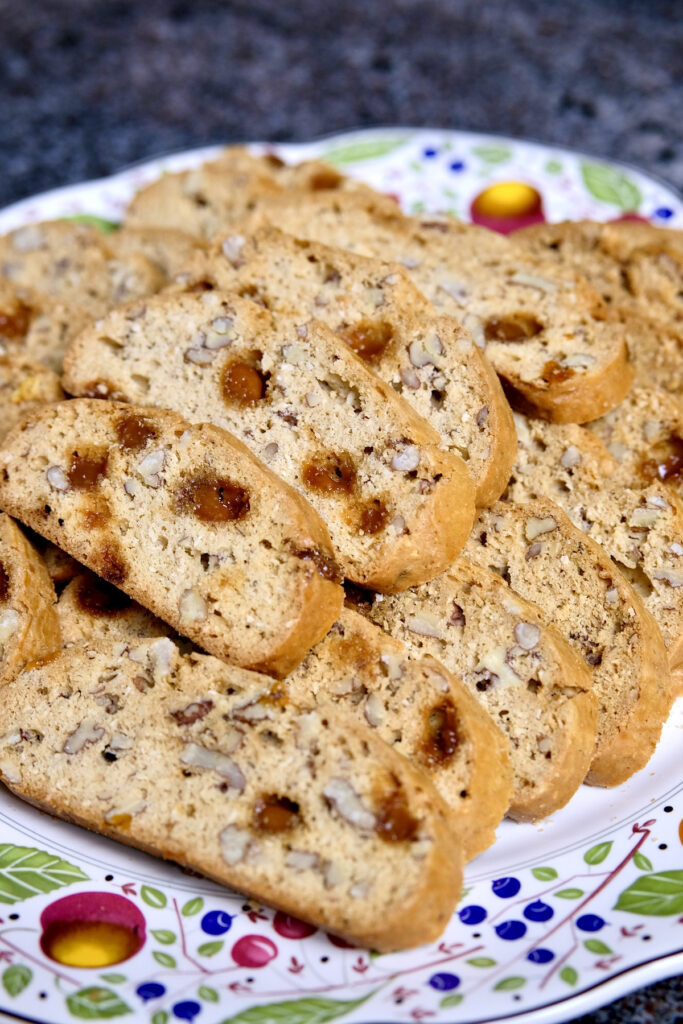 Sliced biscotti arranged on a multi-colored plate set on black marble.