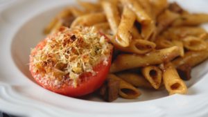 Pasta Tiella in white bowl served with Stuffed Tomato