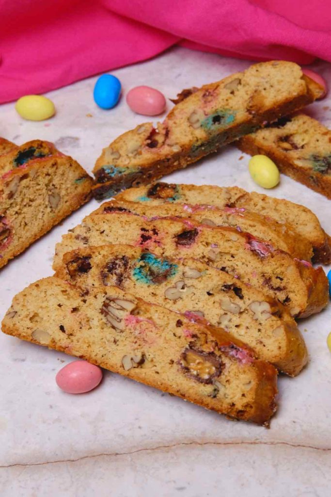 Robin-Egg Biscotti on marble board with pink linen in background and robin egg candies scattered about