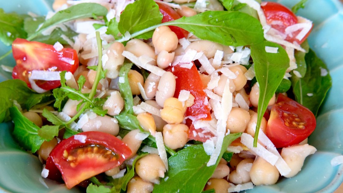 Sicilian Bean and tomato Salad in blue serving bowl garnished with Grana Padano