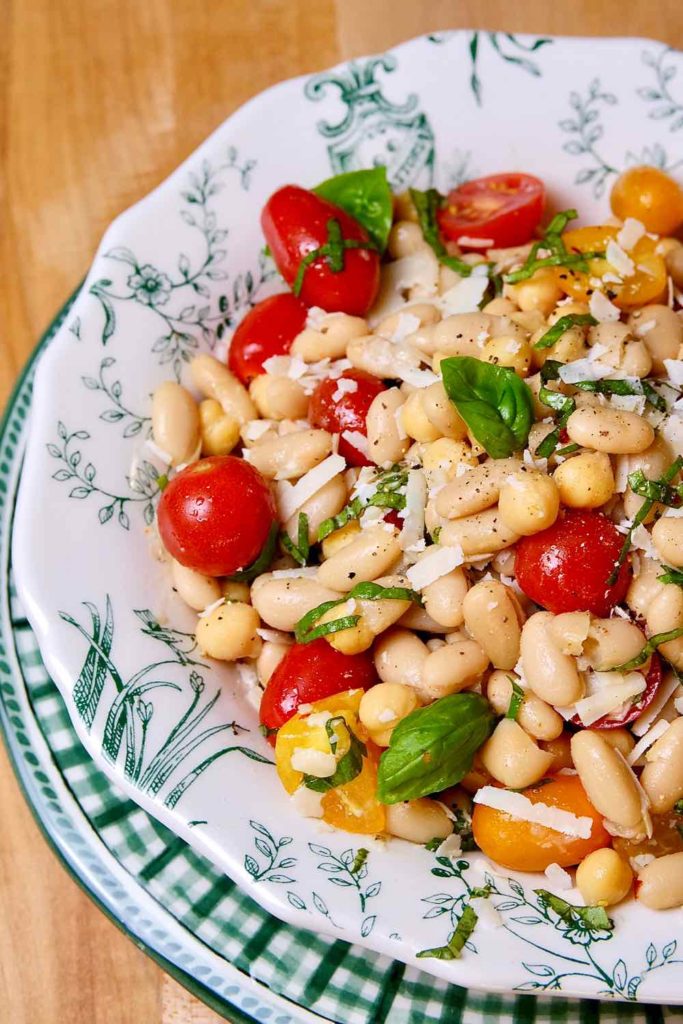 Sicilian Bean and Tomato Salad served in white and green Tosacana Bowl with Green and White Gingham charger plate underneath.