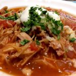 Sopa Seca de Fideo in white bowl garnished with sour cream and cilantro