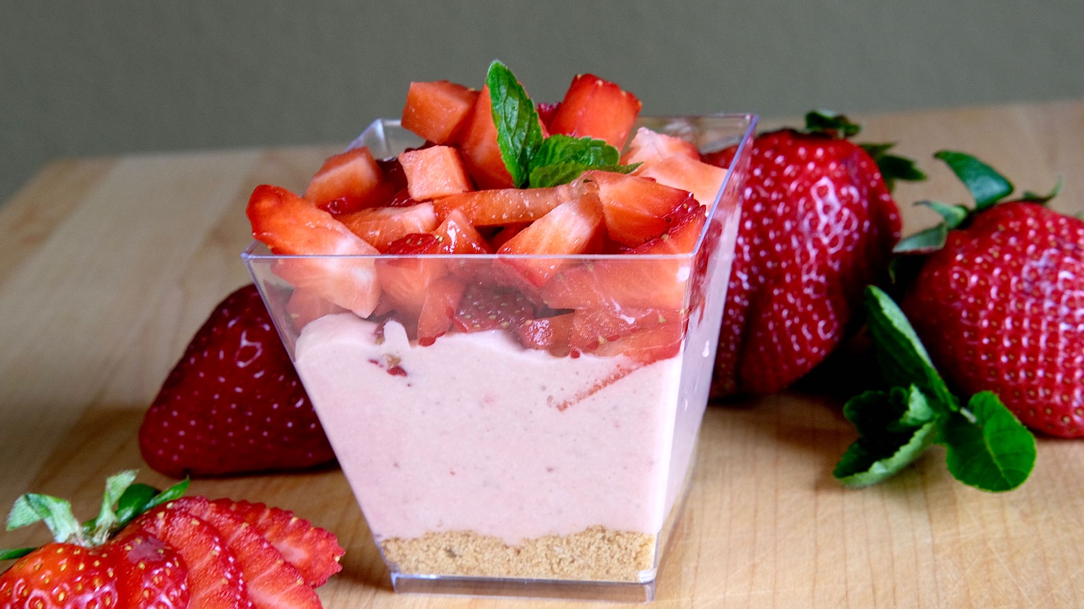 Strawberry Chiffon Cheesecake Parfait garnished with chopped fresh Straweberries and Strawberries in foreground