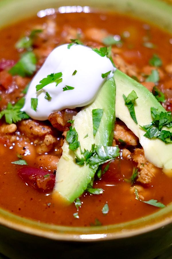 Spicy tomato soup garnished with avocado, sour cream, cilantro