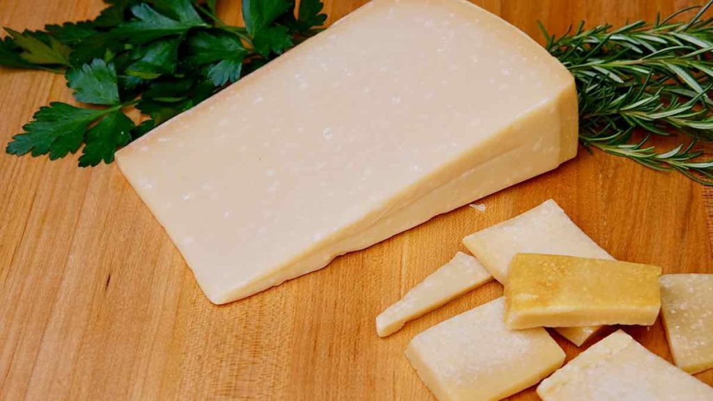 Parmesan Cheese Rinds and Parmesan Wedge on maple board with fresh herbs