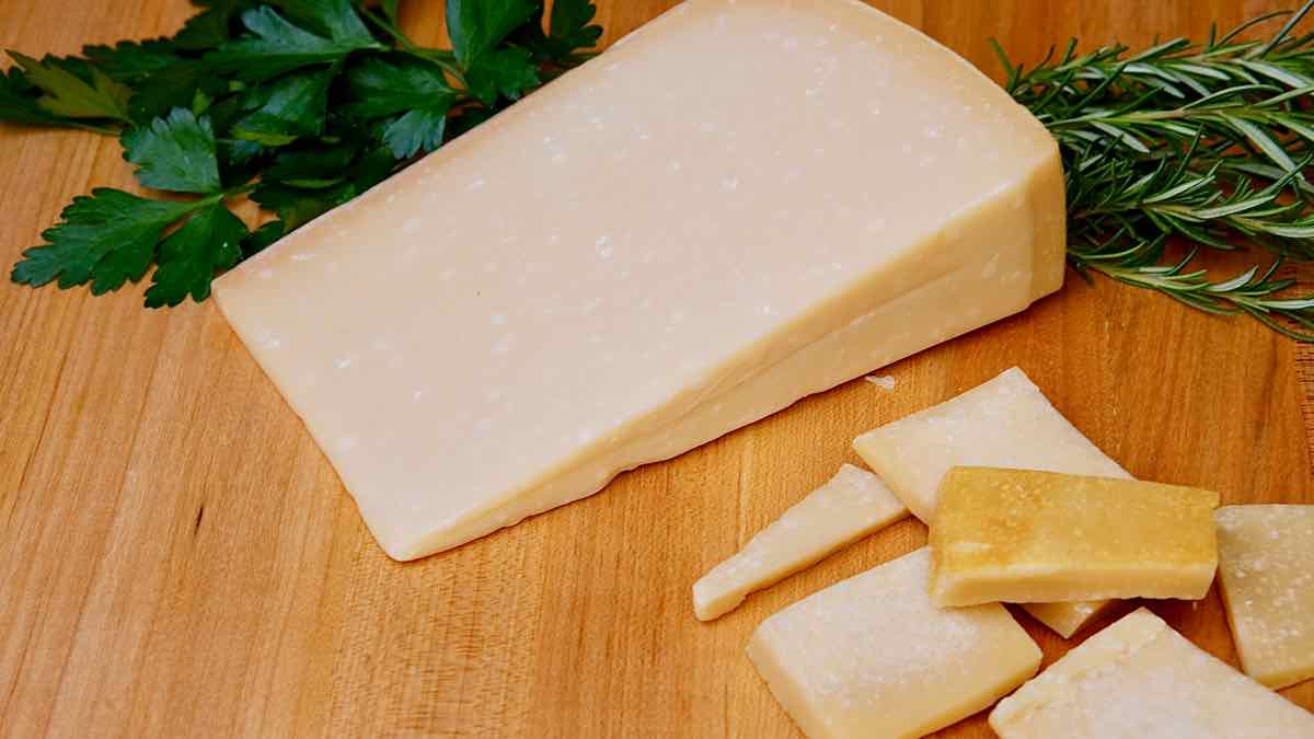 Parmesan Cheese Rinds and Parmesan Wedge on maple board with fresh herbs