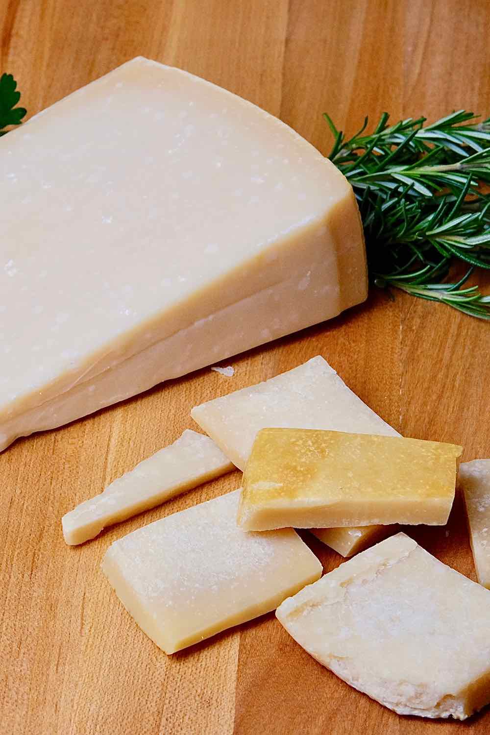 Parmesan Cheese Rinds and Parmesan cheese wedge on a maple board with fresh herbs