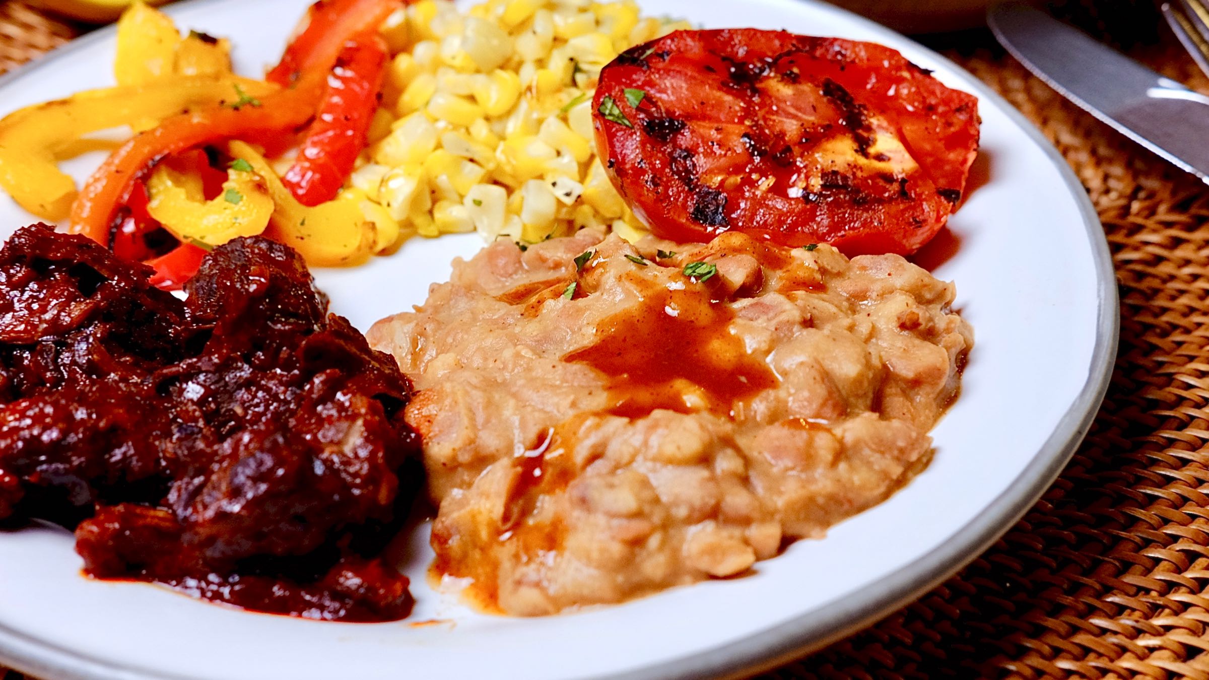 Skinny Refried Beans on white plate with grilled tomatoes, corn and Carne
