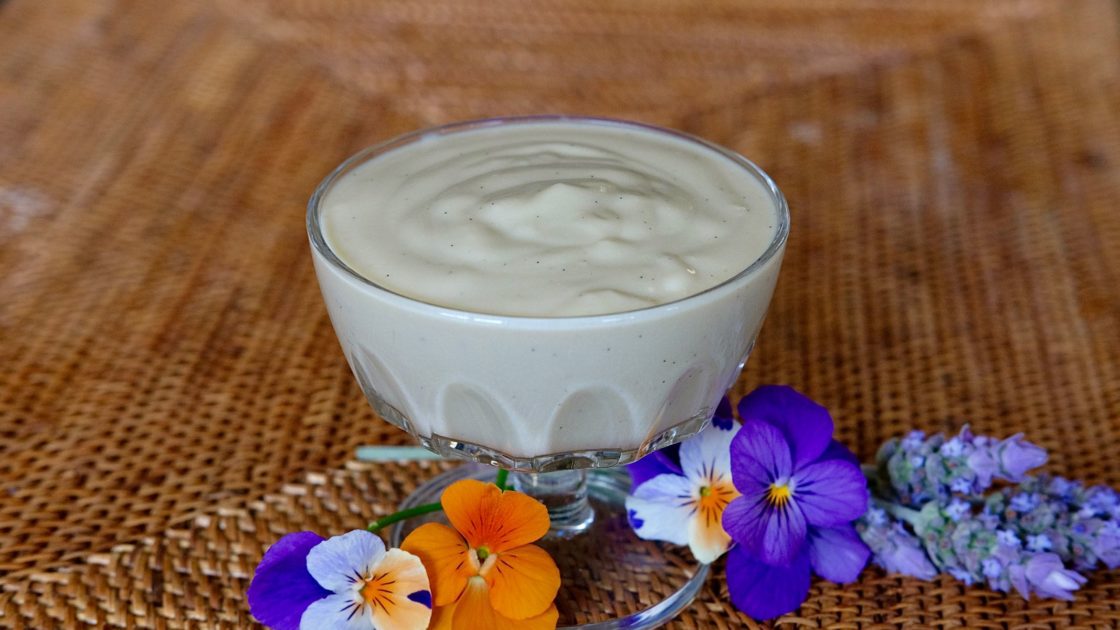 Vanilla Pudding with Almond Milk in glass serving dish with pansies in foreground