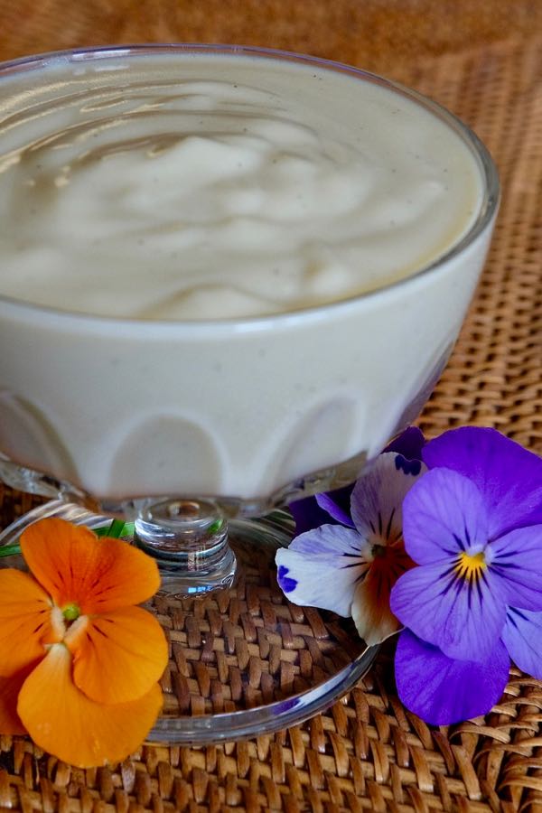 Vanilla Pudding with Almond Milk in a glass sherbet dish with pansies in foreground