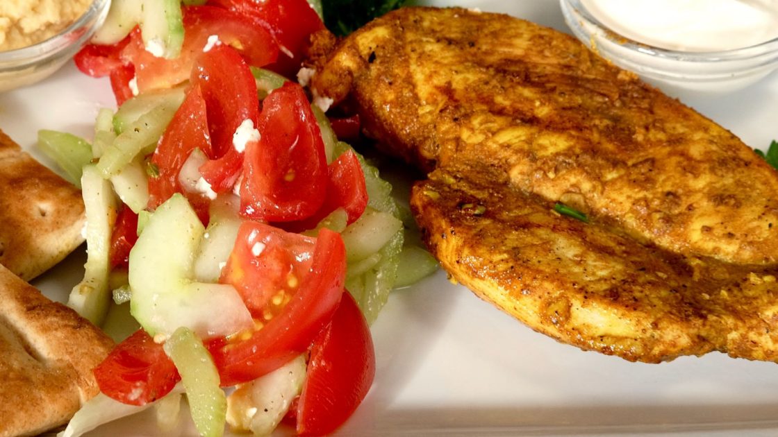 Chicken Shawarma with Tomato Cucmber Salad, Hummus and Yogurt Sauce on White Serving Plate