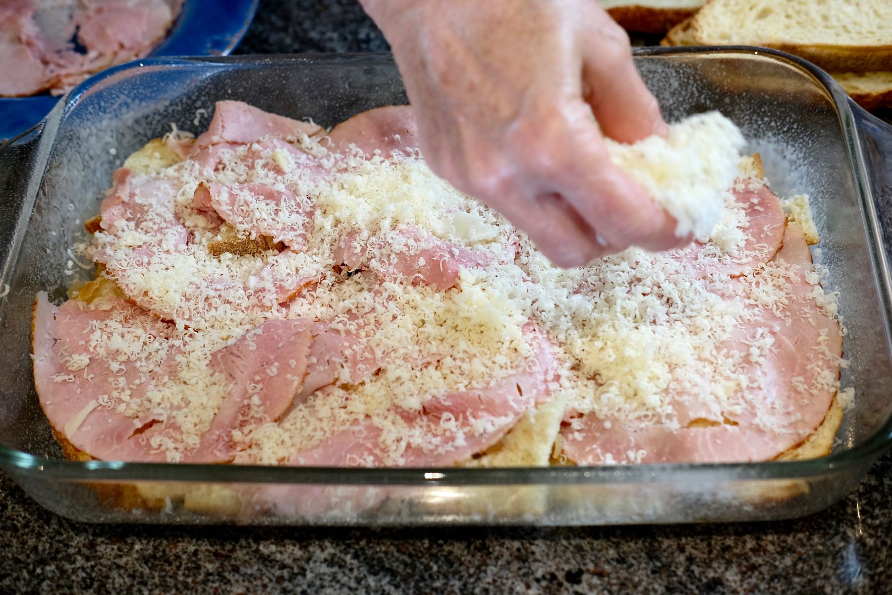 Layering the ham and cheese over first layer of bread in glass baking dish.