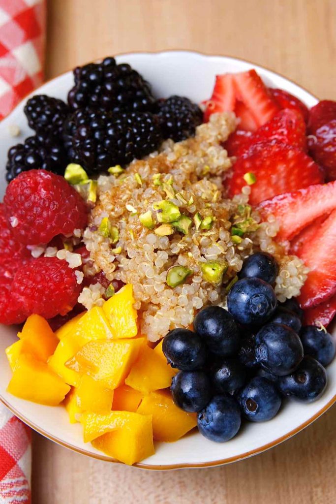 Quinoa Breakfast Bowl served with blueberries, strawberries, blackberries, raspberries and chopped mangos.  Then garnished with chopped pistachios. 