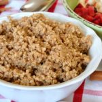 Cinnamon Almond Quinoa in white bowl with spoon and green bowl overlay with chopped nectarines and plums