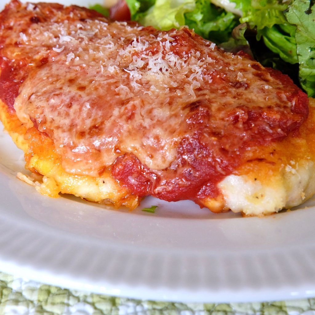 Chicken Parmesan with Mixed Green Salad on white plate