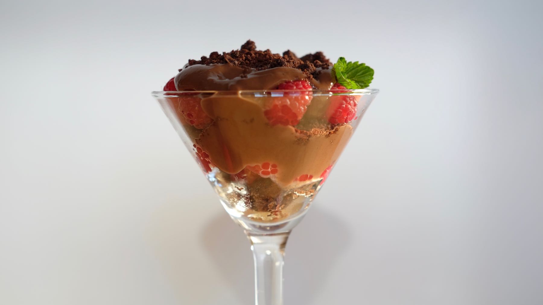 Chocolate Raspberry Parfait in a martini glass with Chocolate Sand and Fresh Mint