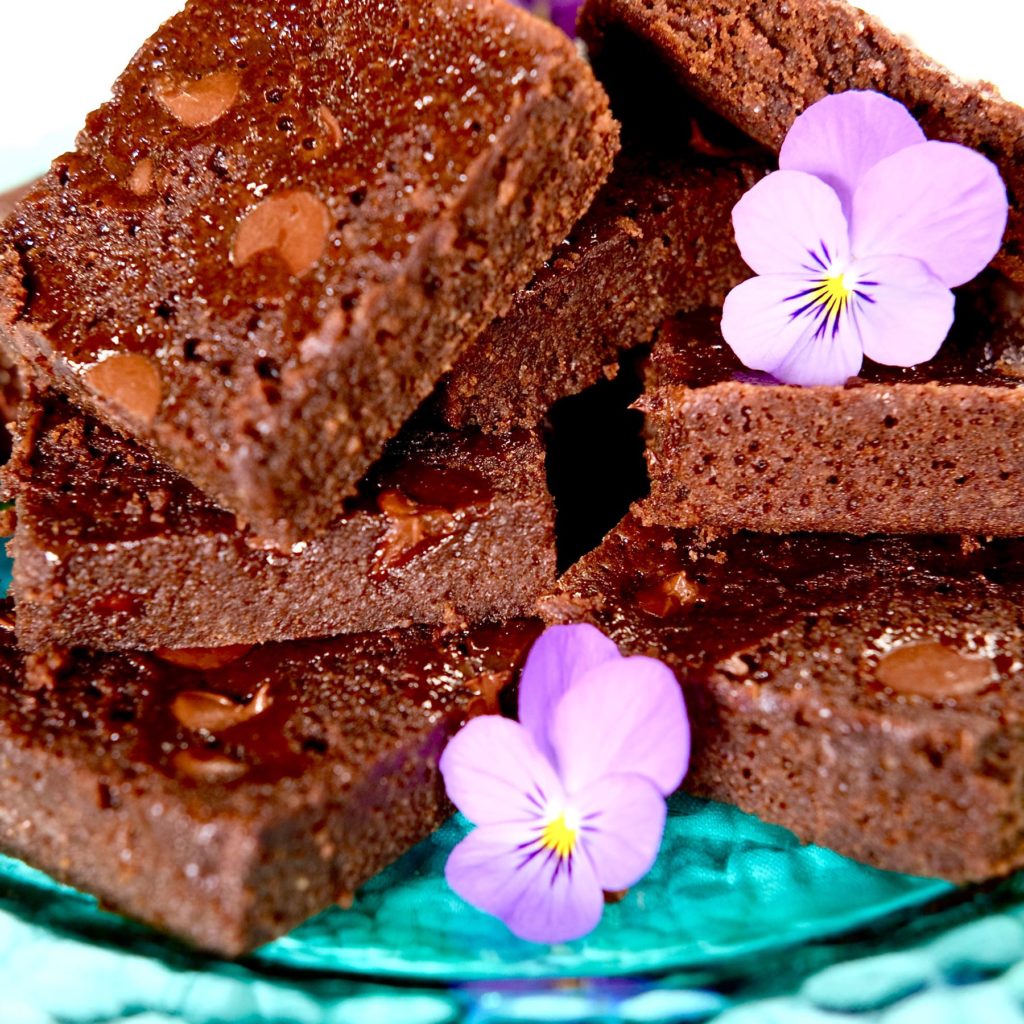 Double Chocolate Brownies on teal glass plate garnished with violas