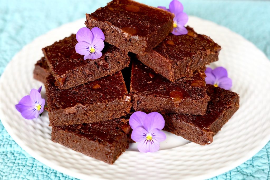 Double Chocolate Brownies on white plate on turquoise overlay garnished with lavender violas