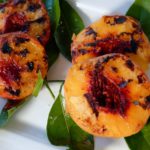 Grilled Peaches on overlay of lemon leaves on a white plate