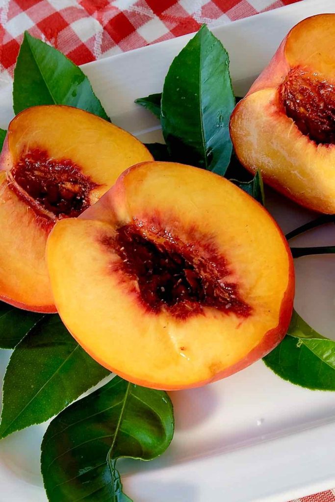 Peach Halves on white plate ready to go to grill.