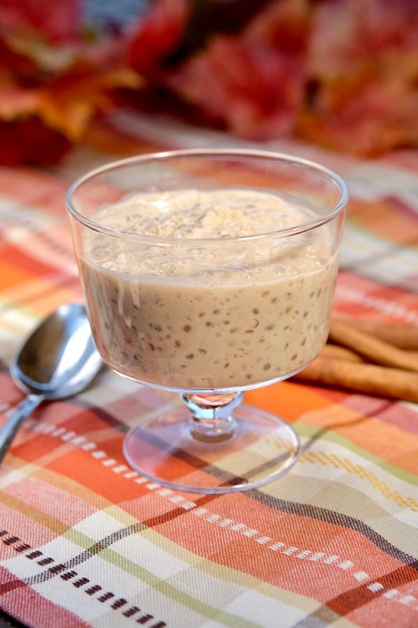 Cinnamon Tapioca Pudding in glass serving dish with cinnamon sticks in background and spoon to the side of dish.