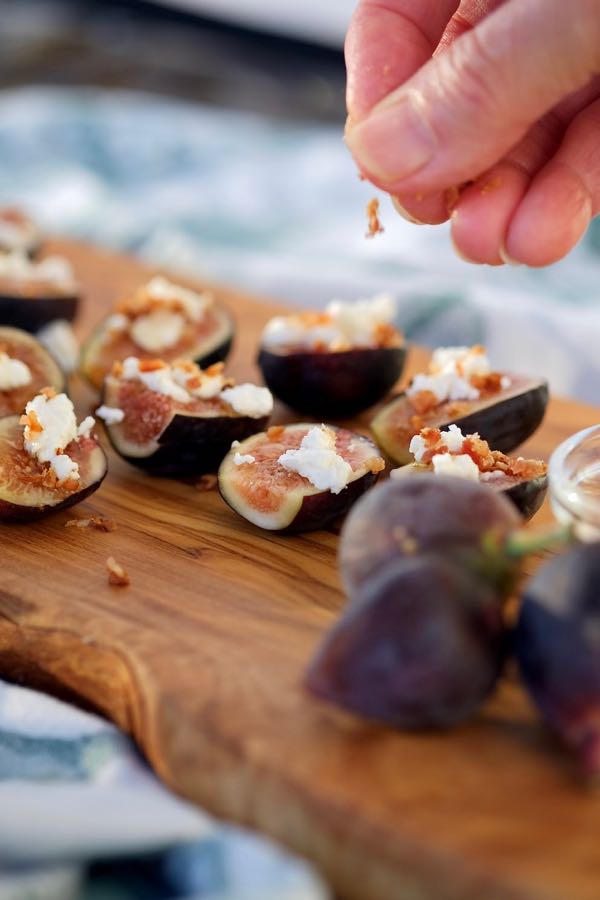 Easy Fig Appetizer sprinkled with goat cheese and drizzled with honey served on an olive wood board.