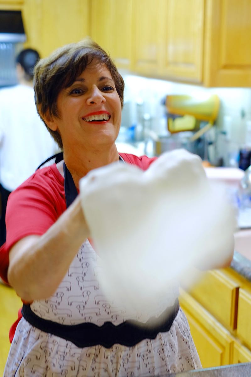 Mia tossing pizza dough in her kitchen.