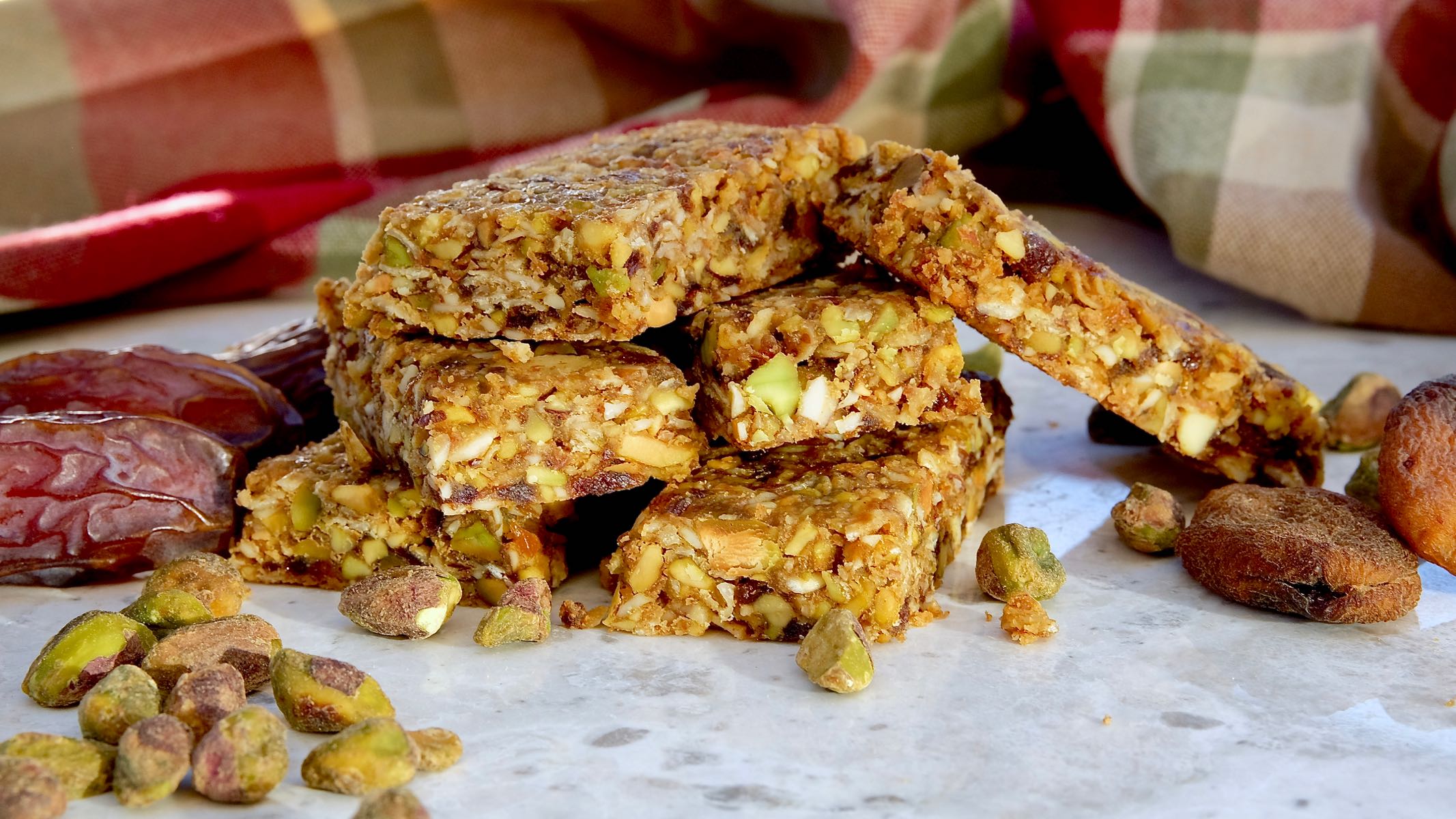 Pistachio-Apricot Granola Bars on white marble with burgundy and green plaid linen in background