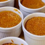 Pumpkin Custard in white ramekin cups set on walnut board.