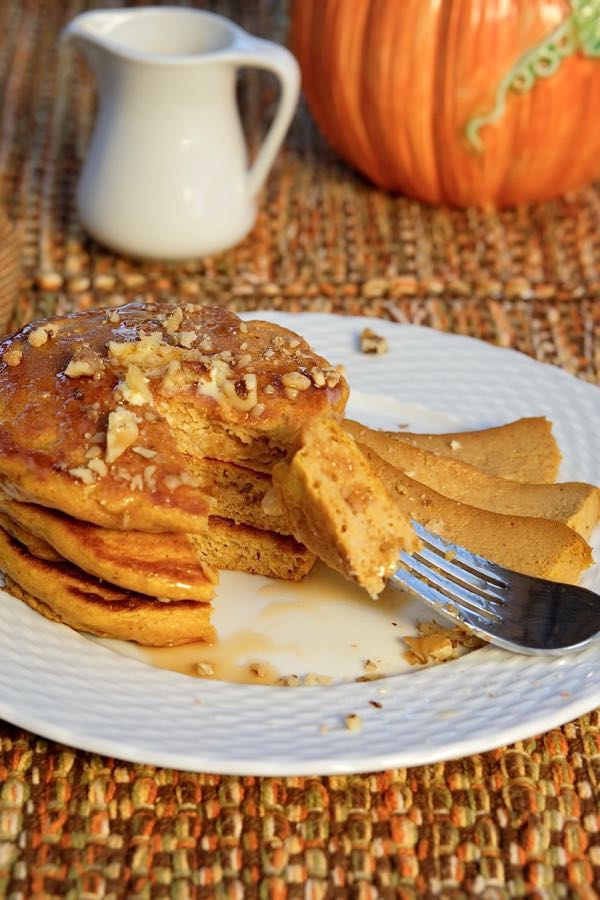 Fluffy Pumpkin Spice Pancakes served with Pumpkin Custard and Toasted Hazelnuts on white plate