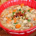 Hearty Turkey Chowder served in a red bowl with baguette in background