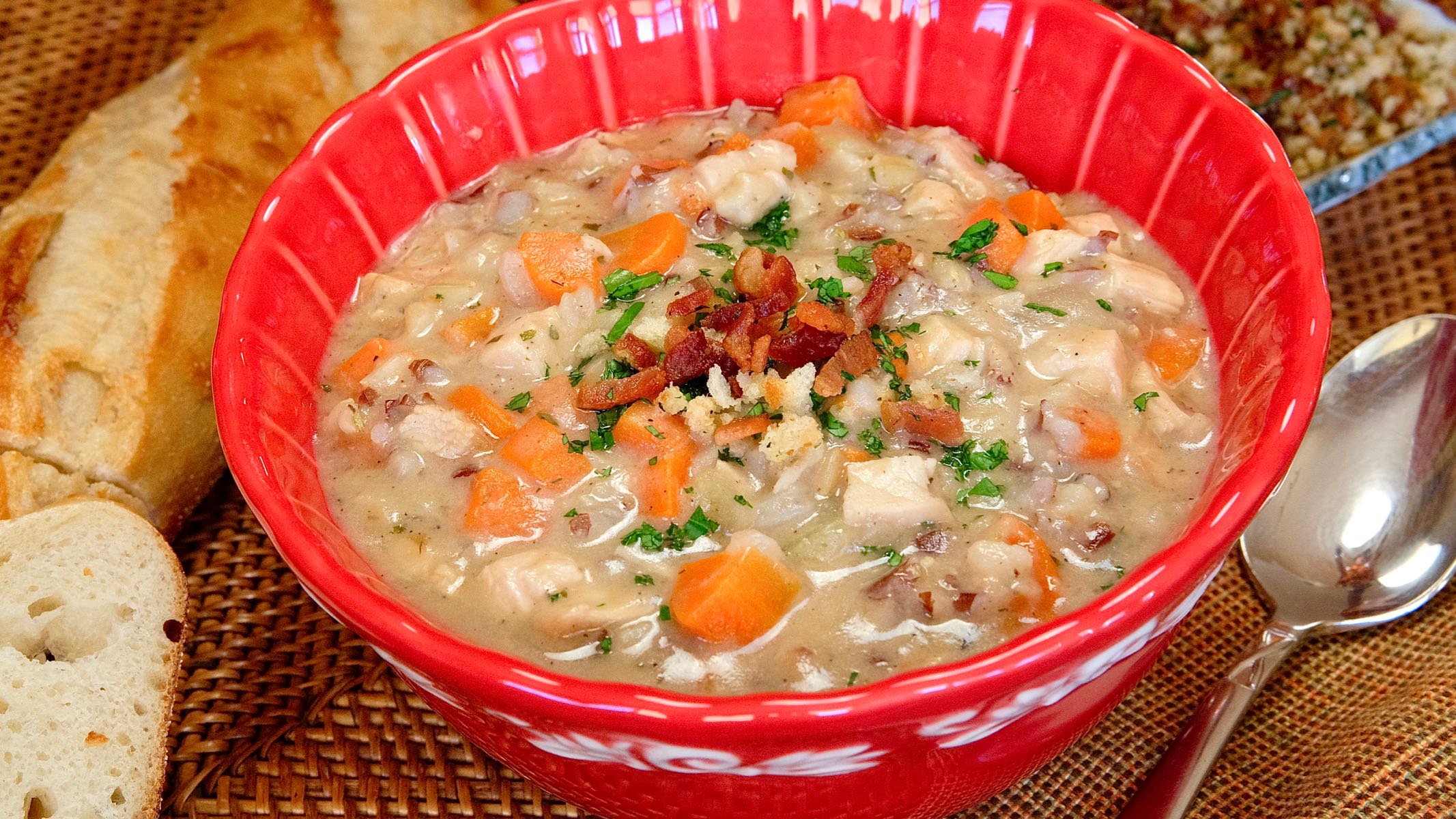 Hearty Turkey Chowder served in a red bowl with baguette in background