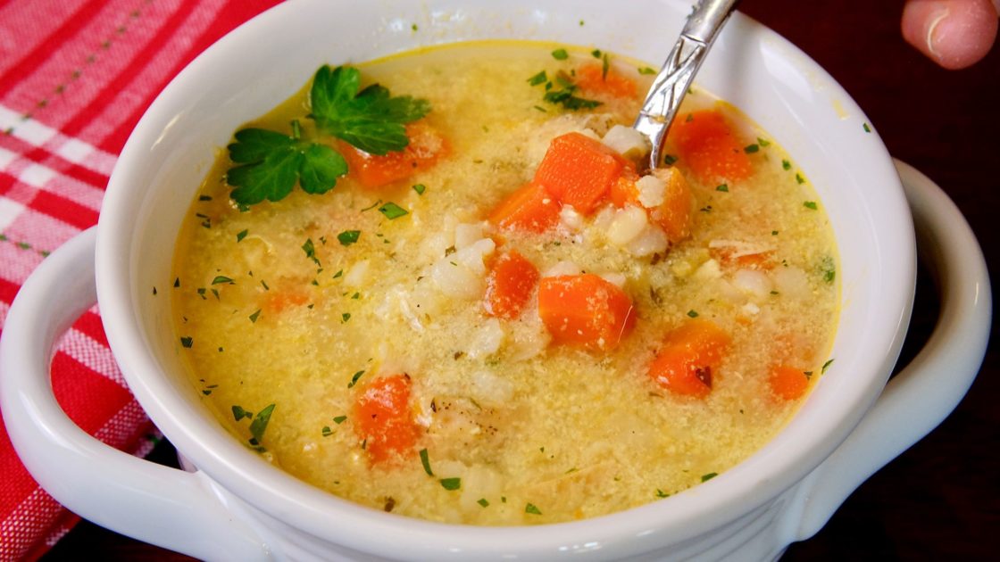 Greek-Style Lemon Chicken Soup in white bowl with red linen in background