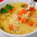 Greek-Style Lemon Chicken Soup in white bowl with red linen in background