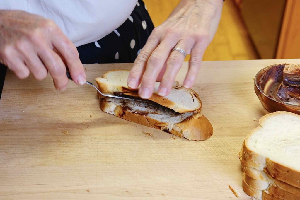 Nutella and Mascarpone filling being stuffed into the bread with offset spatula on a maple cutting board