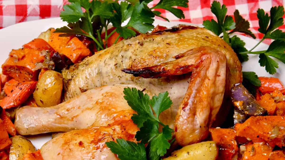 Lemon-Herb Roasted Chicken on platter with roasted potatoes and carrots