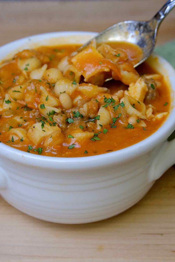 Tuscan Bean Soup in white soup bowl with a spoonful of soup being lifted from bowl.