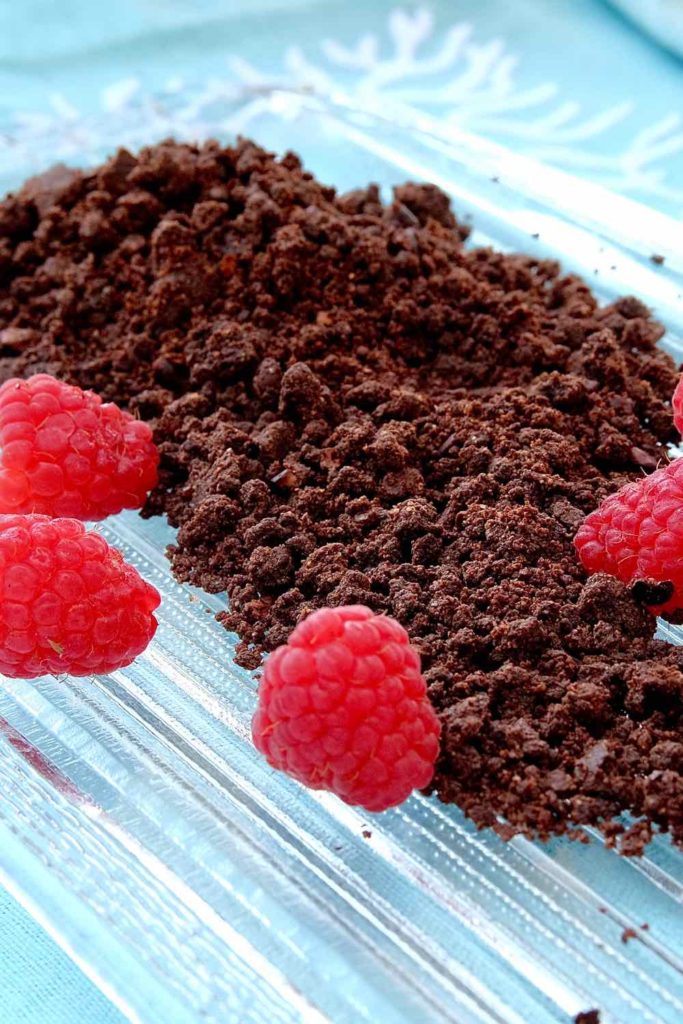 Chocolate Sand garnished with fresh raspberries on a glass dish with blue linen underlay.  