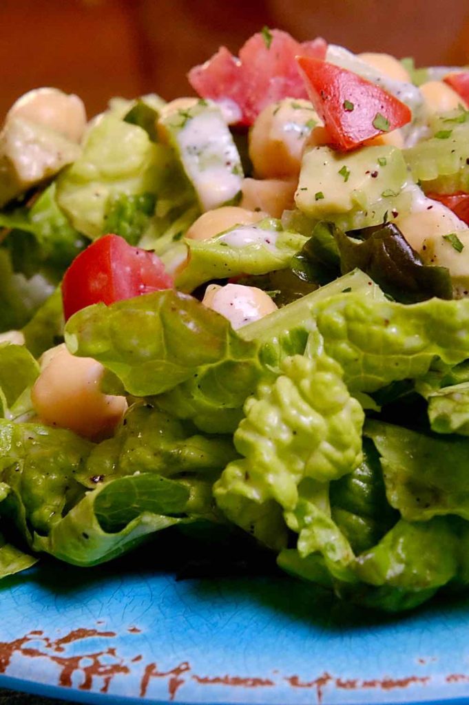 Green Mediterranean Salad on blue plate with Lemon-Sumac Dressing and yogurt sauce. 