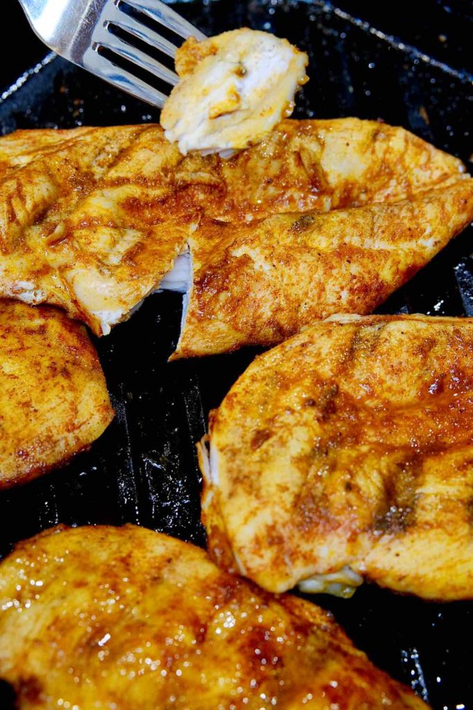 Easy Baked Chicken Cutlets seasoned with Bronzeville Seasoning in cast iron griddle.