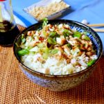 Healthy Hoisin Chicken Bowl with Rice in blue rice bowl set on a rattan mat with blue linen and chopsticks in background