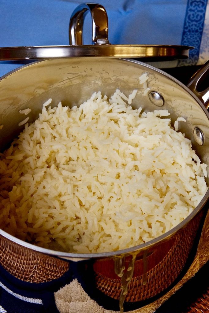 Sauce pan with perfect fluffy white rice on blue linen unerlay