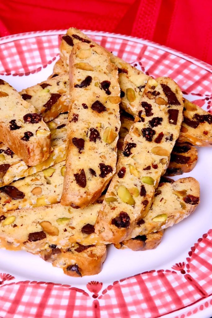 Chocolate Cranberry Holiday Biscotti on red and white gingham plate with red linen in background. 