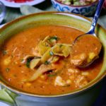 Creamy Chicken Tortilla Soup in green soup bowl with spoon shot, garnished with tortilla strips and cilantro