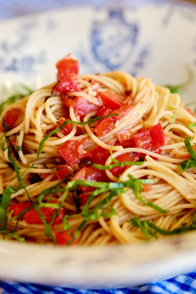 Linguine pasta with a fresh tomato sauce and garnished with shredded basil in a white and blue pasta bowl.