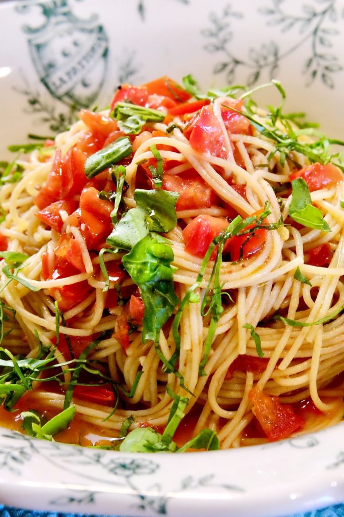 Linguine pasta with fresh and easy tomato sauce garnished with chiffonade basil served in a white and green Italian bowl.