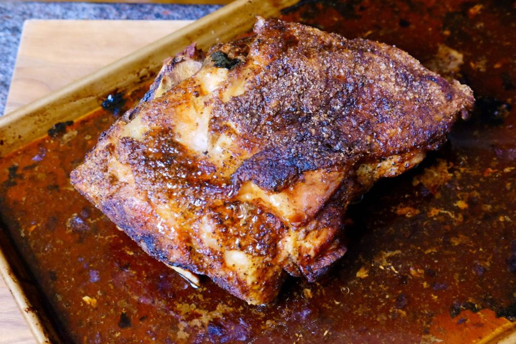 Roasted Pork Butt sitting in roasting pan with juices.